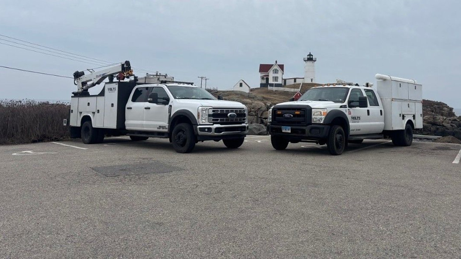 Two VOLTS service trucks at a coastal lighthouse