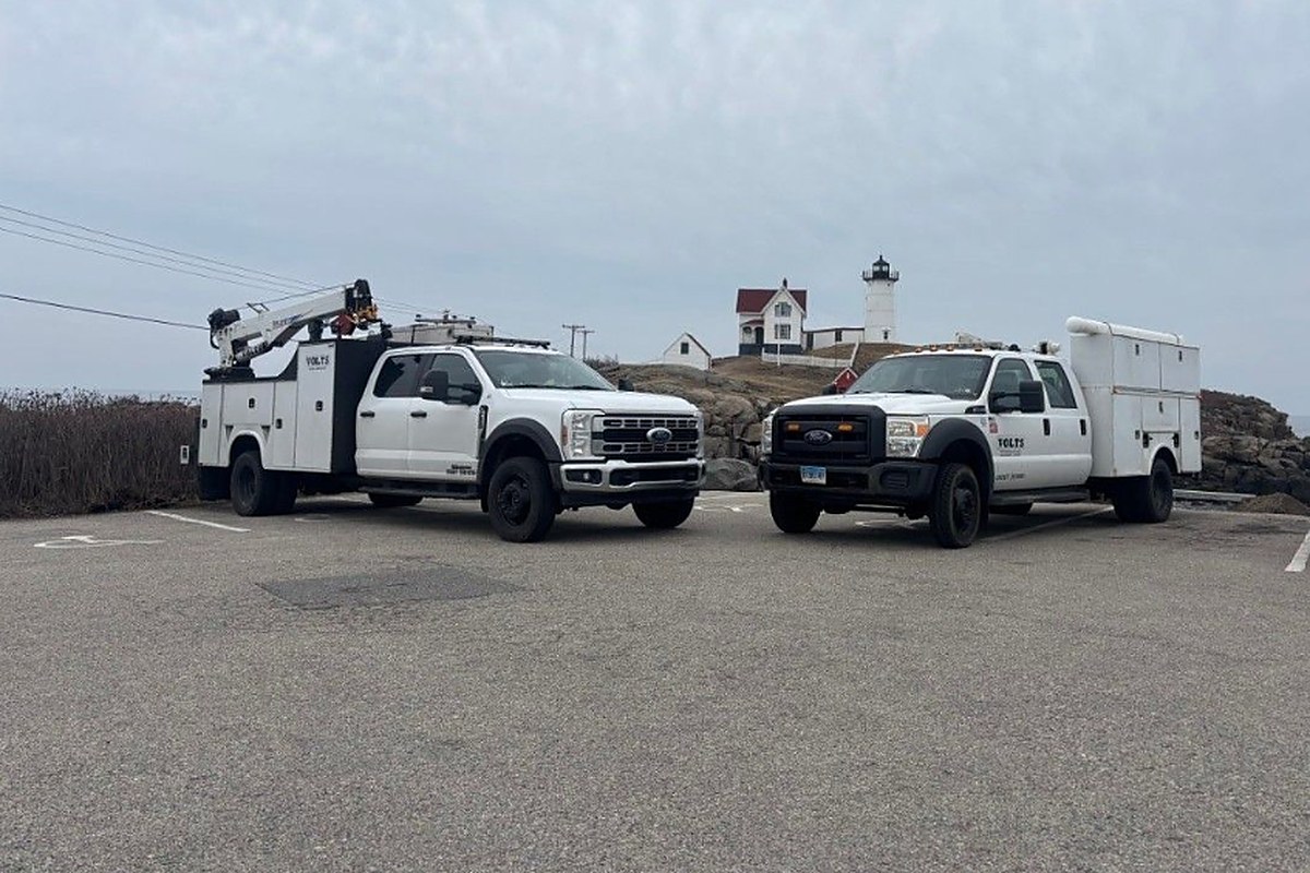 Two VOLTS service trucks at a coastal lighthouse